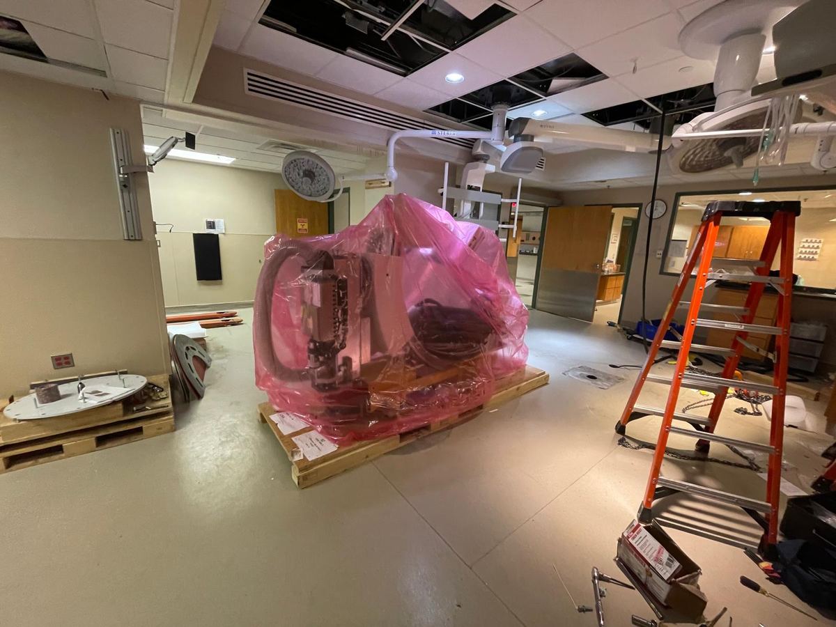 Shrink-wrapped imaging equipment staged on pallets in a room under construction