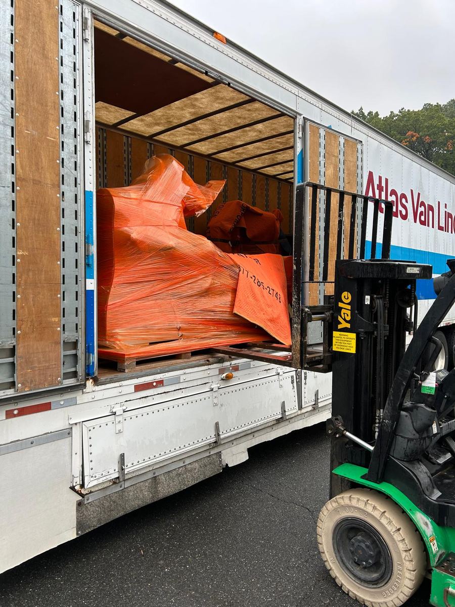 Forklift loading shrink-wrapped medical equipment into a moving trailer